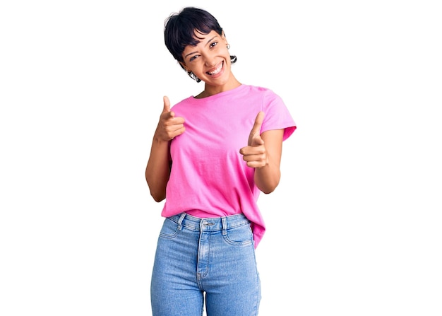 Foto grátis jovem morena com cabelo curto, vestindo roupas casuais, apontando o dedo para a câmera com cara de feliz e engraçada. boas energias e vibrações.