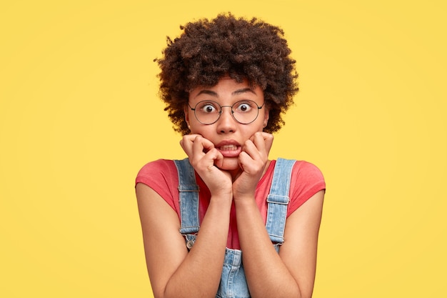 Jovem morena com cabelo encaracolado e macacão jeans