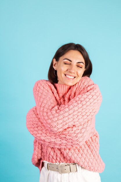 Jovem morena com suéter rosa isolada na parede azul