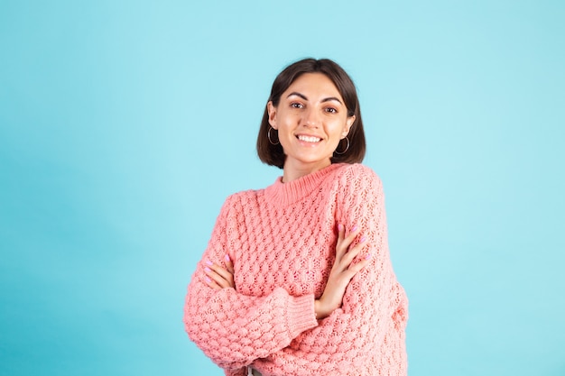 Jovem morena com suéter rosa isolada na parede azul