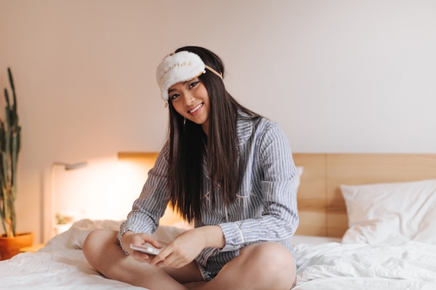 Foto grátis jovem morena de pijama listrado sorrindo docemente