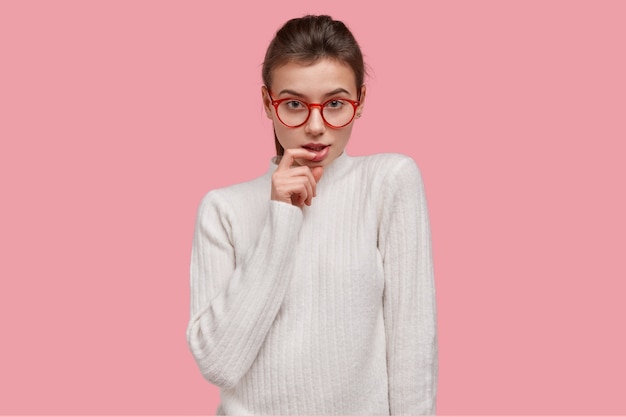 Jovem morena de suéter branco e óculos vermelhos
