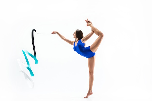 Foto grátis jovem morena ginasta treinando exercícios calilistênicos com fita azul