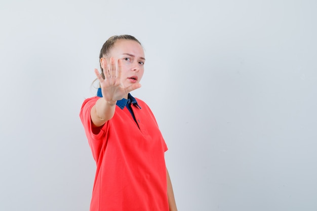 Jovem mostrando gesto de pare com uma camiseta e parecendo irritada