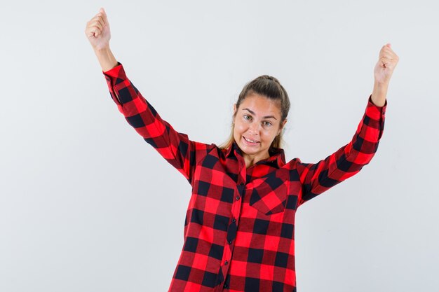 Jovem mostrando gesto de vencedor com uma camisa xadrez e parecendo feliz