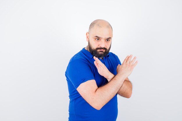 Jovem mostrando gesto fechado na camisa azul e olhando sério. vista frontal.