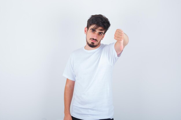 Jovem mostrando o polegar para baixo em uma camiseta branca e parecendo confiante