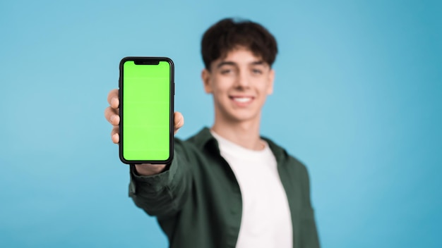 Jovem mostrando smartphone com tela verde