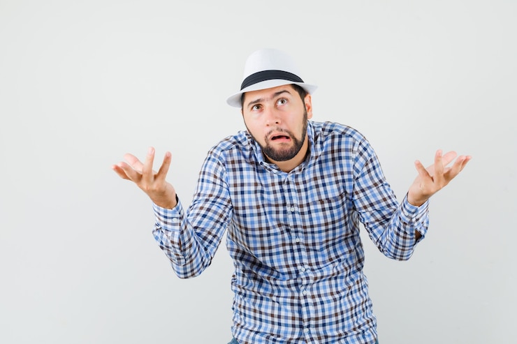 Foto grátis jovem mostrando um gesto desamparado com uma camisa xadrez, chapéu e parecendo perplexo