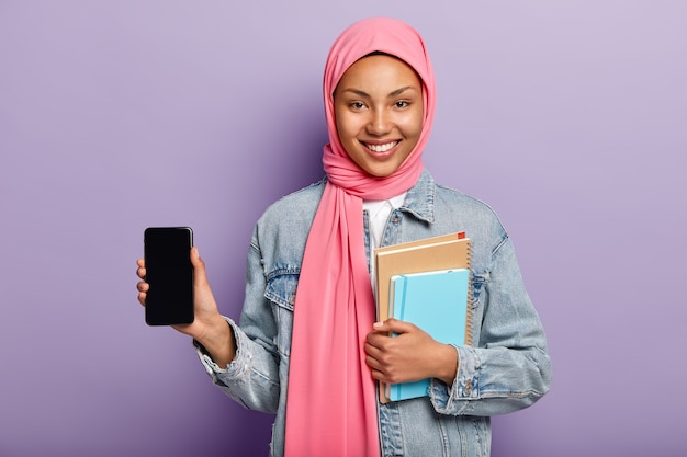 Jovem muçulmana encantadora e satisfeita com um hijab rosa na cabeça