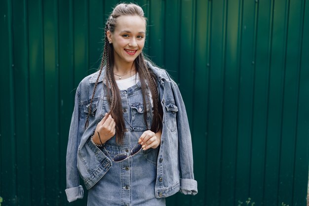 Jovem muito atraente em roupas jeans e óculos em um fundo verde escuro simples com um lugar vazio para o texto