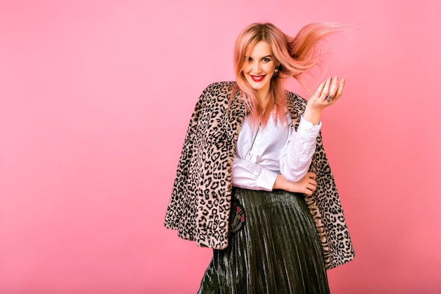 Jovem muito sexy mulher magnífica brincando com seus cabelos, vestindo roupa de cocktail espumante de noite e casaco da moda impresso de leopardo de pele, fundo rosa, emoções positivas.
