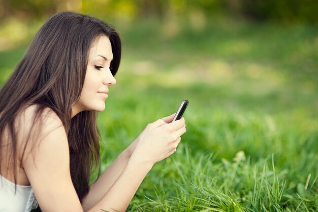 Jovem mulher a enviar mensagens de texto no prado