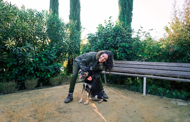 Jovem mulher acaricia seu cachorro no parque ao pôr do sol. conceito de amizade, felicidade, companhia.