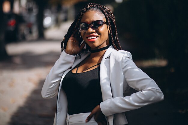 Jovem mulher africana vestida de terno branco do lado de fora da rua