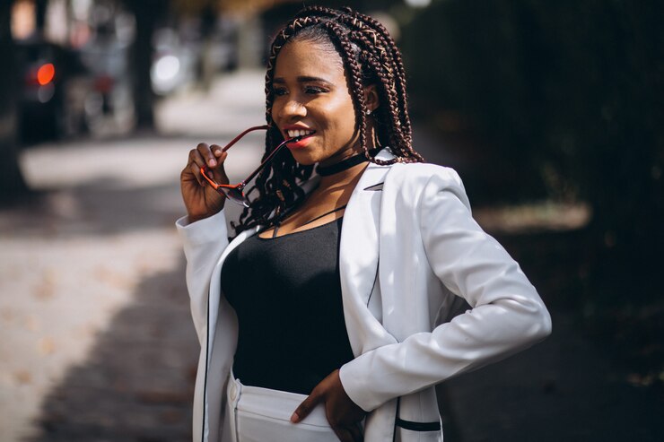 Foto grátis jovem mulher africana vestida de terno branco do lado de fora da rua
