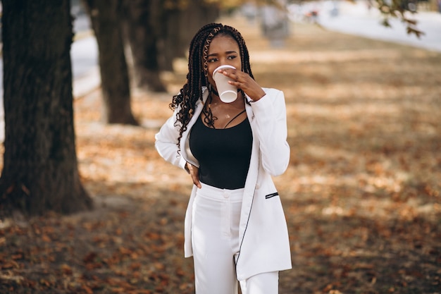 Jovem mulher africana vestida de terno branco no parque