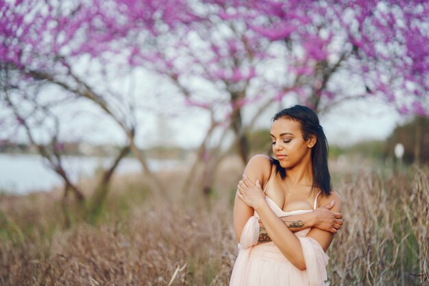 Jovem mulher afro-americana, as árvores com a linda cor rosa