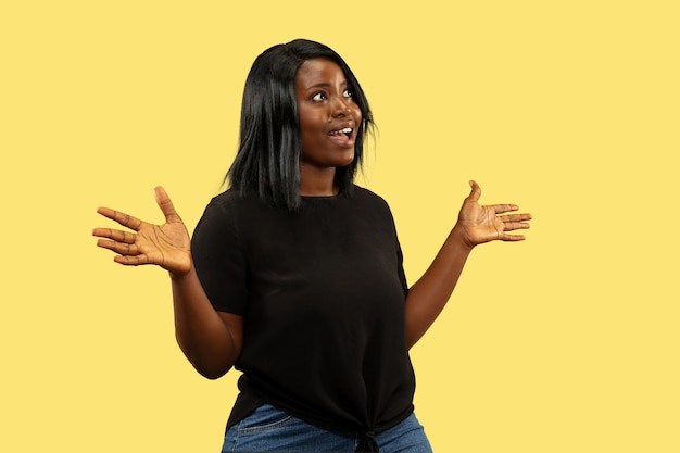 Foto grátis jovem mulher afro-americana isolada no espaço amarelo, expressão facial. belo retrato feminino de meio corpo.