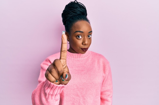 Foto grátis jovem mulher afro-americana vestindo suéter de inverno casual apontando com o dedo para cima e expressão de raiva, não mostrando nenhum gesto