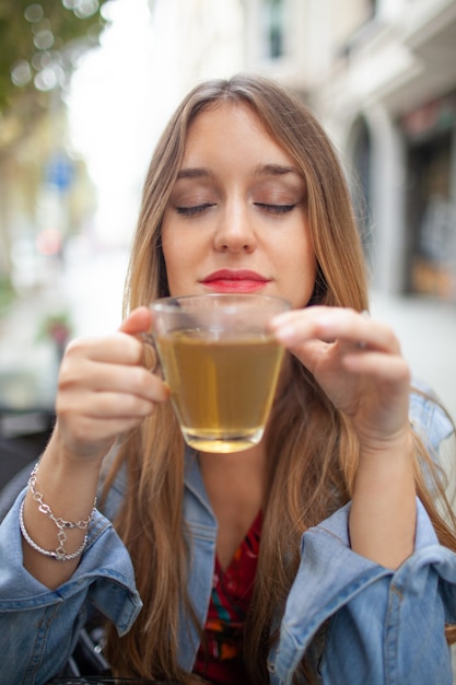Jovem mulher agradável cheirando o chá verde perfumado