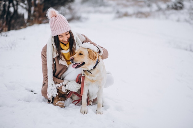 Jovem mulher andando com seu cachorro em um parque de inverno