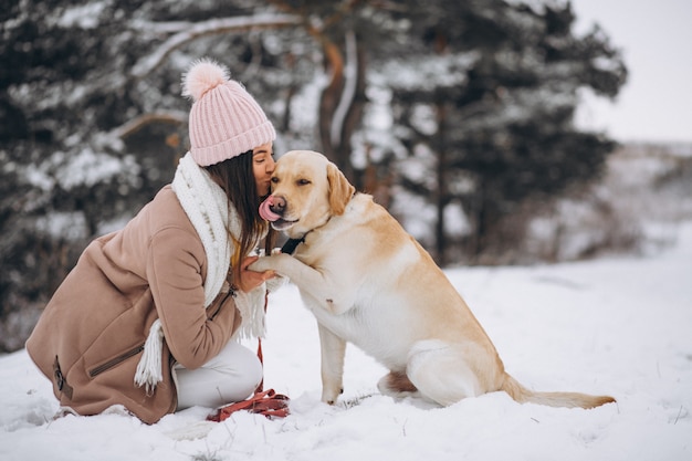 Jovem mulher andando com seu cachorro em um parque de inverno