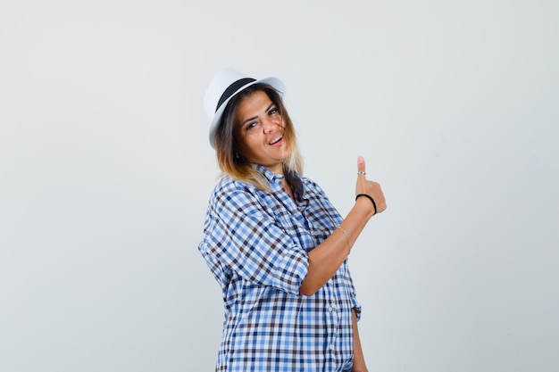 Foto grátis jovem mulher aparecendo o polegar enquanto sorria na camisa quadriculada e olhando positiva.