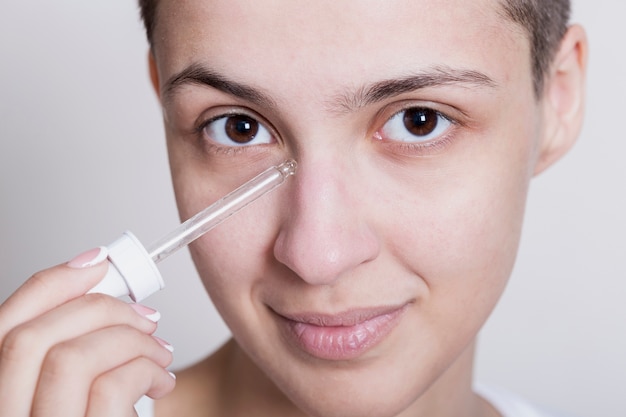 Jovem mulher aplicar produto de cuidados do rosto