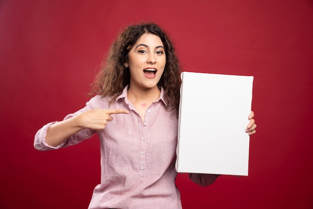 Jovem mulher apontando para uma tela vazia.