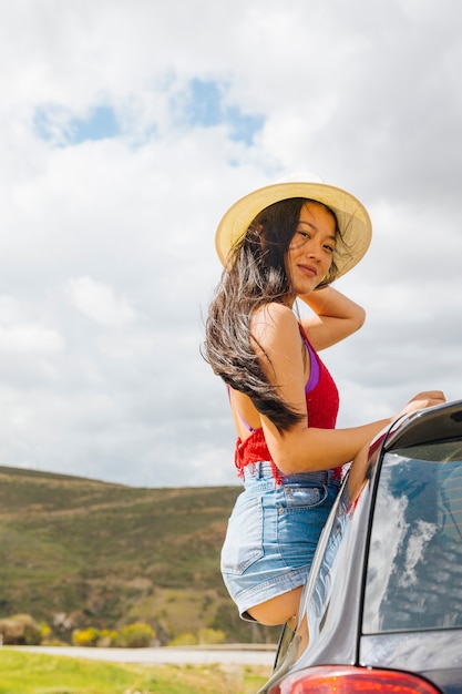 Foto grátis jovem mulher asiática bonita que senta-se fora da janela de carro