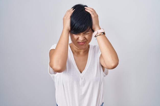 Foto grátis jovem mulher asiática com cabelo curto em pé sobre fundo isolado sofrendo de dor de cabeça desesperada e estressada porque dor e enxaqueca mãos na cabeça