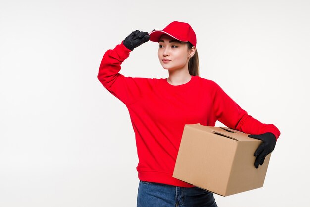 Jovem mulher asiática com trabalhador de serviço de entrega de uniforme. Mulher segurando a caixa com atraente sorriso isolado.