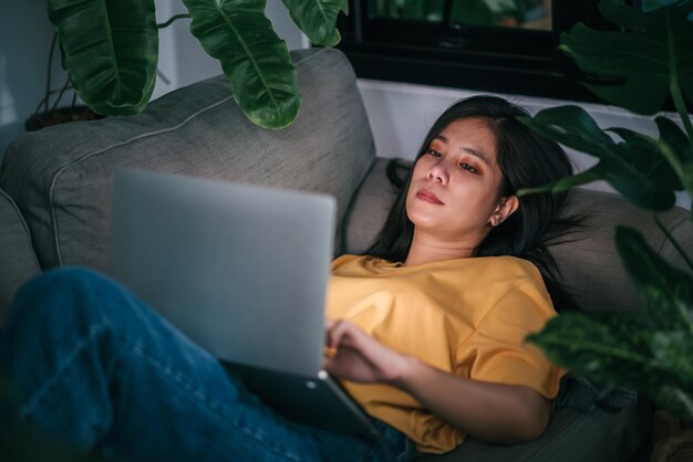 Jovem mulher asiática freelancer trabalhando à noite na sala de estar enquanto trabalha em casa conceito de saúde mental