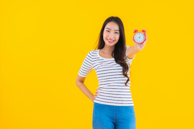 jovem mulher asiática mostrar relógio ou alarme