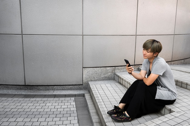 Jovem mulher asiática verificando o telefone ao ar livre