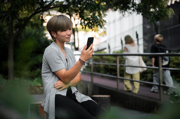 Foto grátis jovem mulher asiática verificando seu smartphone ao ar livre