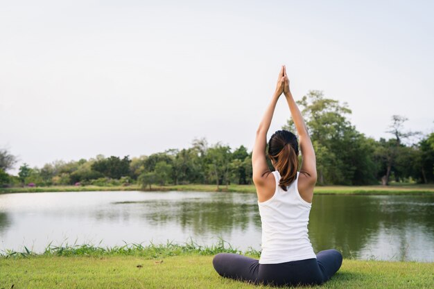 Jovem mulher asiática yoga ao ar livre manter a calma e medita enquanto pratica ioga