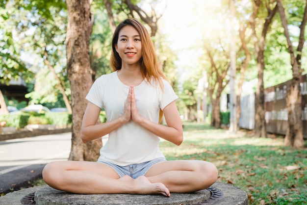 Jovem mulher asiática yoga ao ar livre manter a calma e medita enquanto pratica ioga
