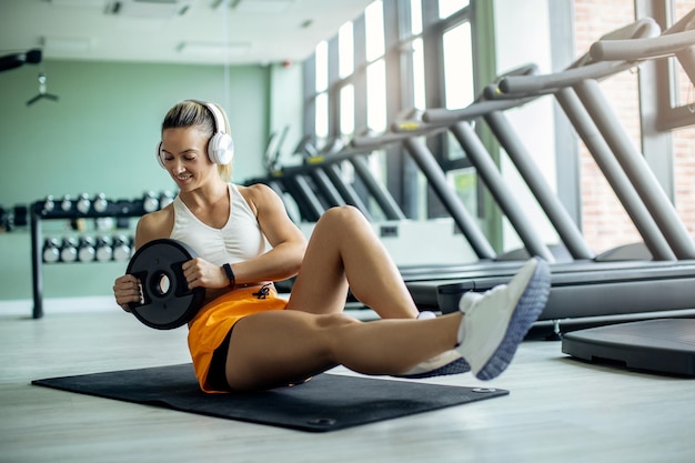Jovem mulher atlética exercitando abdominais com placa de peso em uma academia