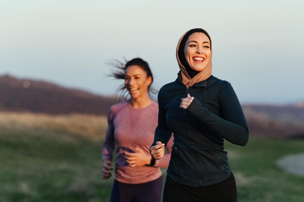 Jovem mulher atlética feliz e seu instrutor de fitness correndo juntos na natureza