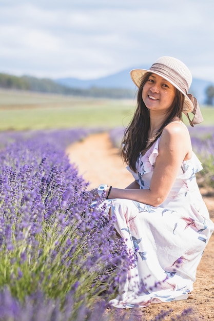 Jovem mulher atraente com um vestido branco está posando para a câmera no campo de Lavanda