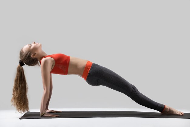 Jovem, mulher atraente, de pé em cima da Plank pose, Gray studi