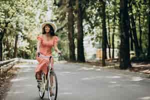 Foto grátis jovem mulher atraente em vestido de bicicleta