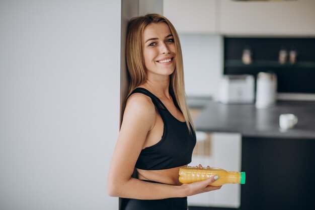 Jovem mulher atraente na cozinha com suco