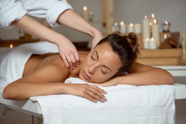 Jovem mulher atraente tendo massagem relaxante no salão spa.