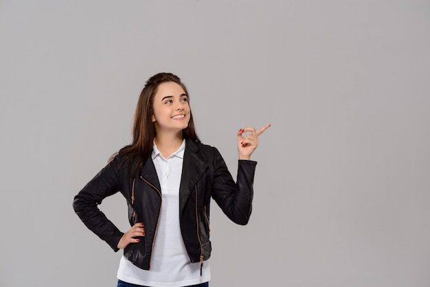 Jovem mulher bonita, apontando o dedo no lado ao longo da parede roxa