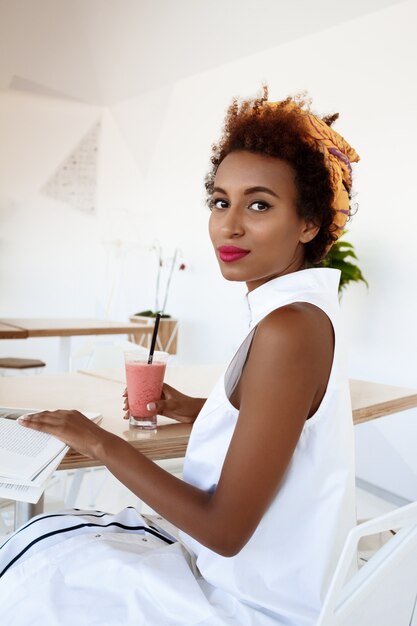 Jovem mulher bonita bebendo suco sorrindo descansando no café