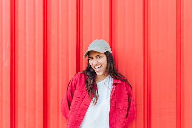 Jovem mulher bonita brincando na frente do pano de fundo de metal vermelho brilhante