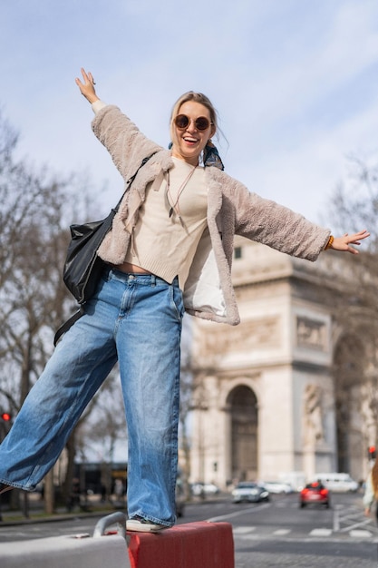 jovem mulher bonita caminha na rua, Paris no fundo do arco do triunfo. O conceito de uma foto de viagem feliz.